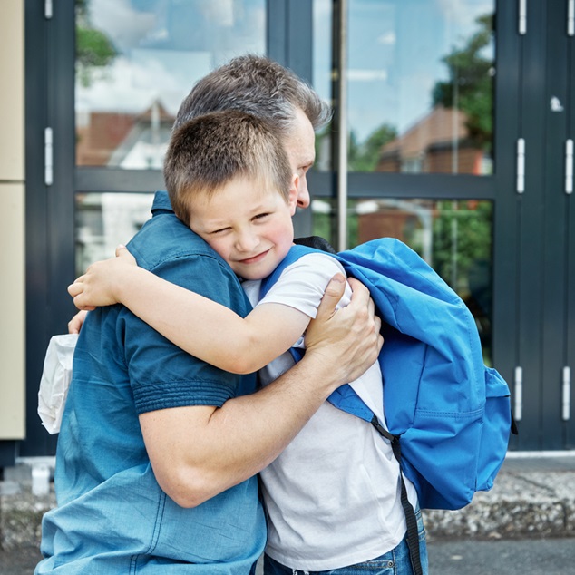 Back to school. Dad sees off, hugs the child before the start of lessons. The new school year. Caring, parent-child relationship.